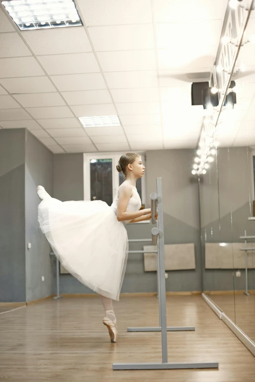 a female ballet dancer dressed in white poses on the metal beam