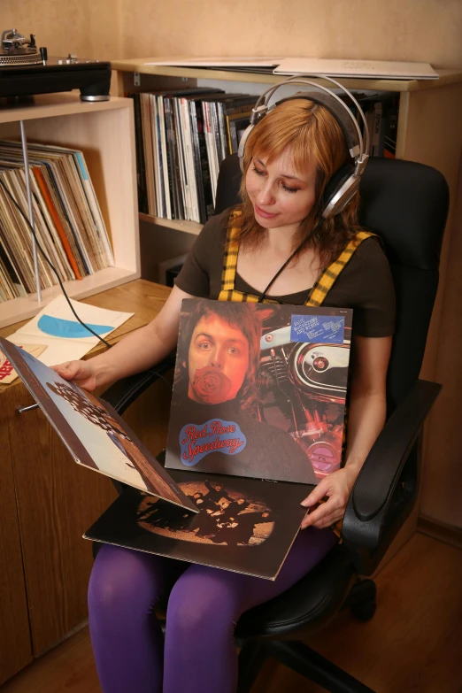 a lady sitting down holding several records on her lap