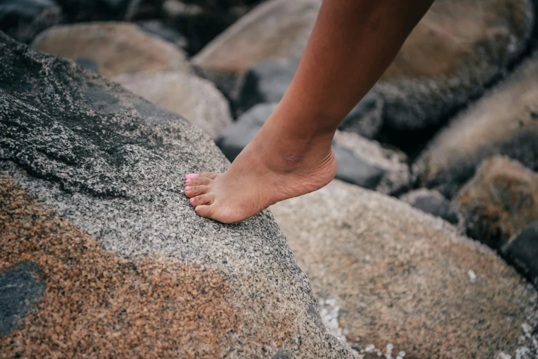 a person stands atop rocks with bare feet