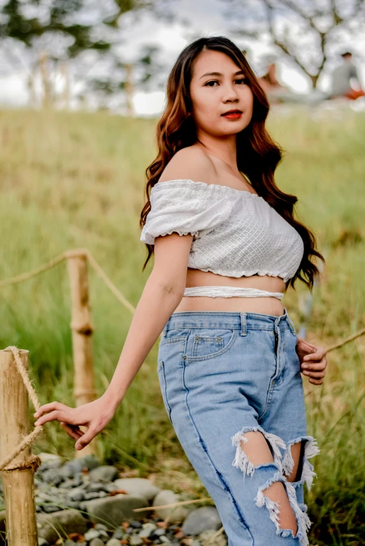 a woman with ripped jeans poses for the camera