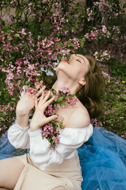 an attractive young woman sitting in a blue dress holding a bouquet