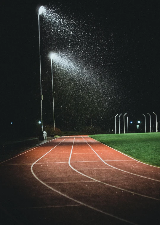 rain falls on an outdoor track at night