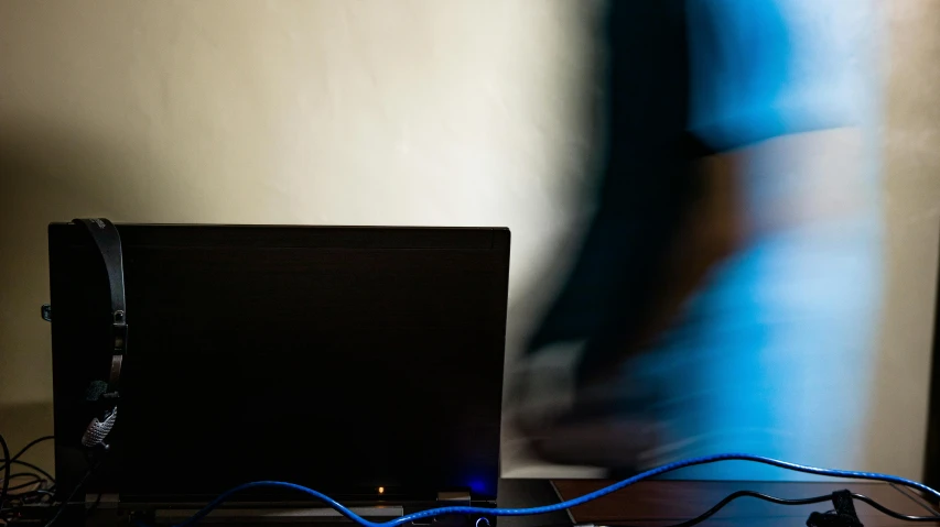 there are wires hanging from a shelf beside a laptop