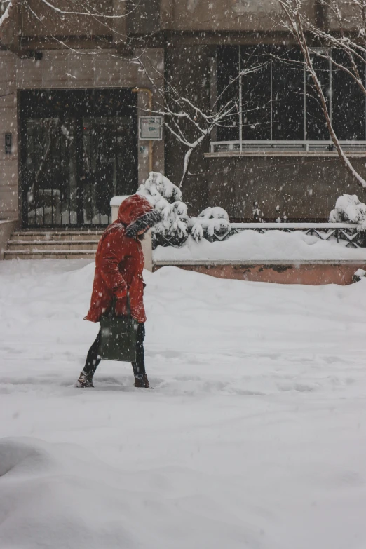 woman walking down snowy street with red coat