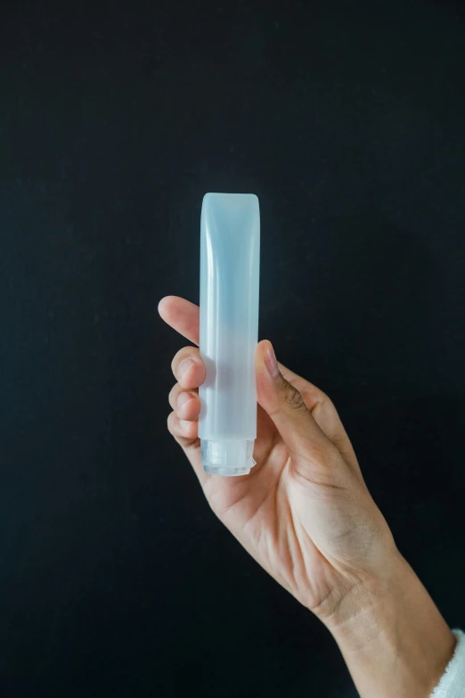 a hand holding a clear plastic device on a black background