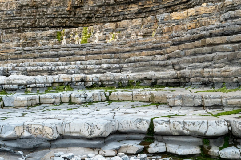 many layers of rocks are stacked next to a lake