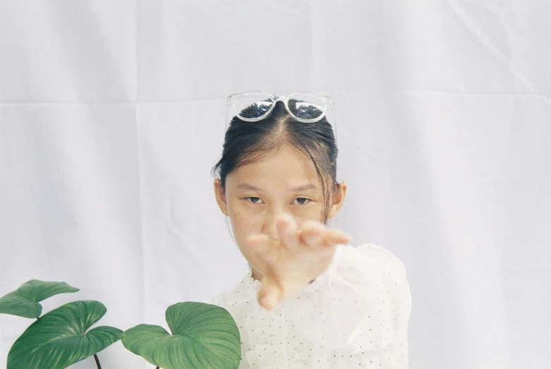 a girl in sunglasses is pointing her finger towards the camera