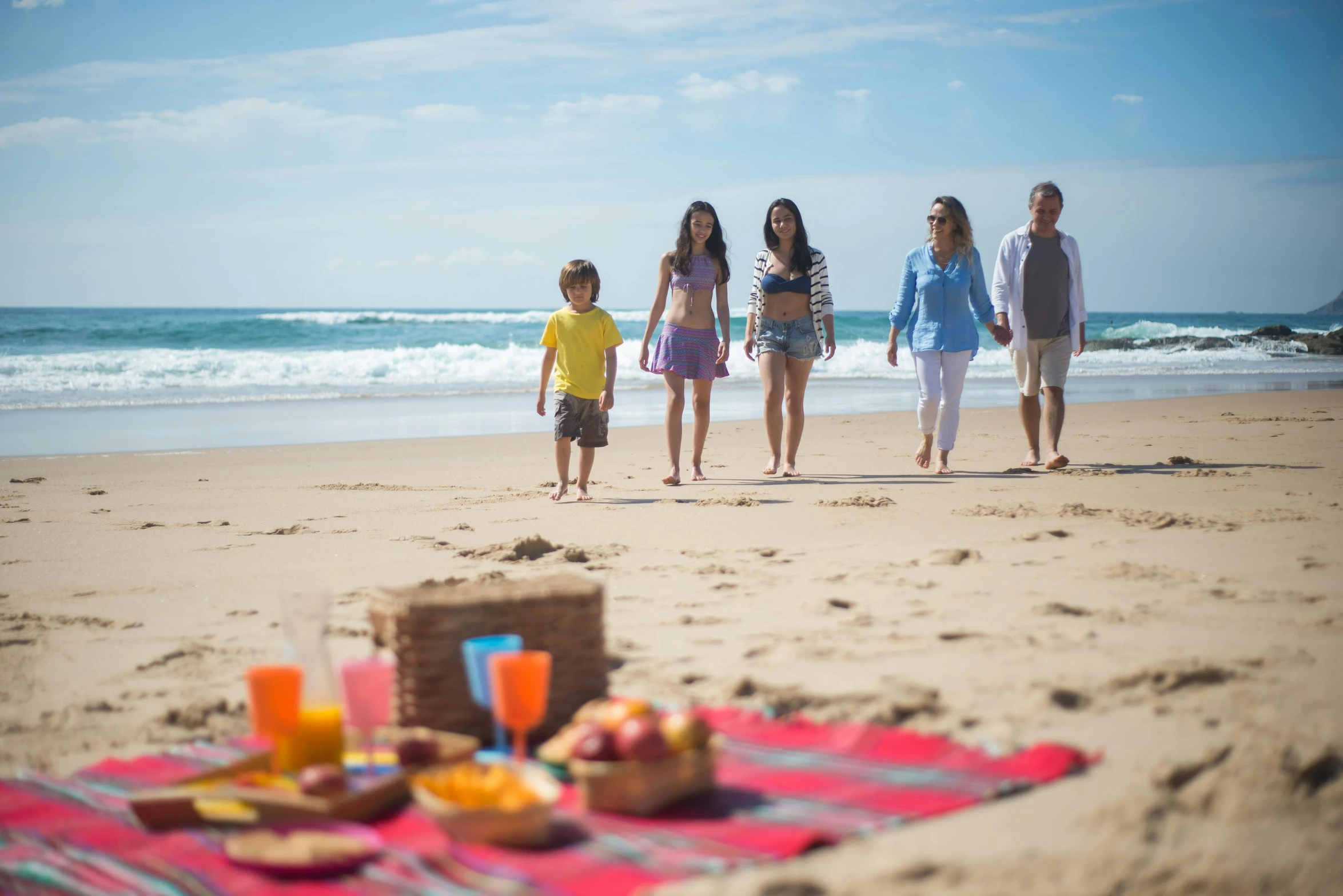 three people walking along the beach with beverages on it