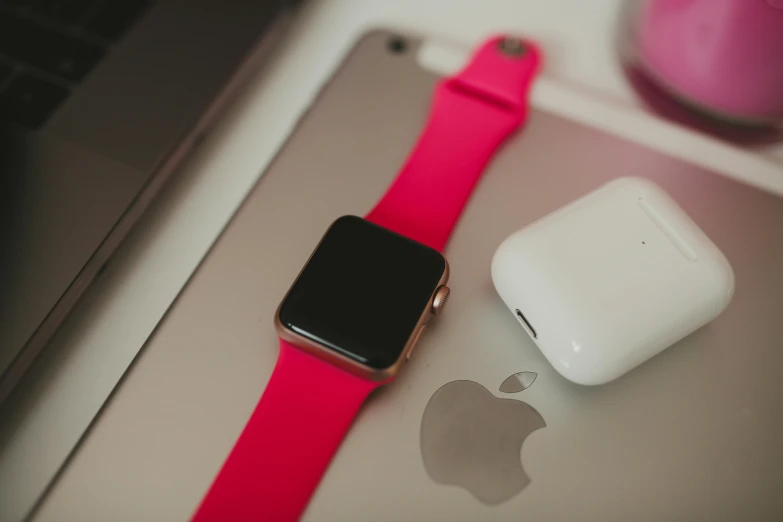 an apple watch and apple airpods on top of a laptop