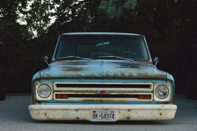 an old rusted out truck sitting in front of some trees