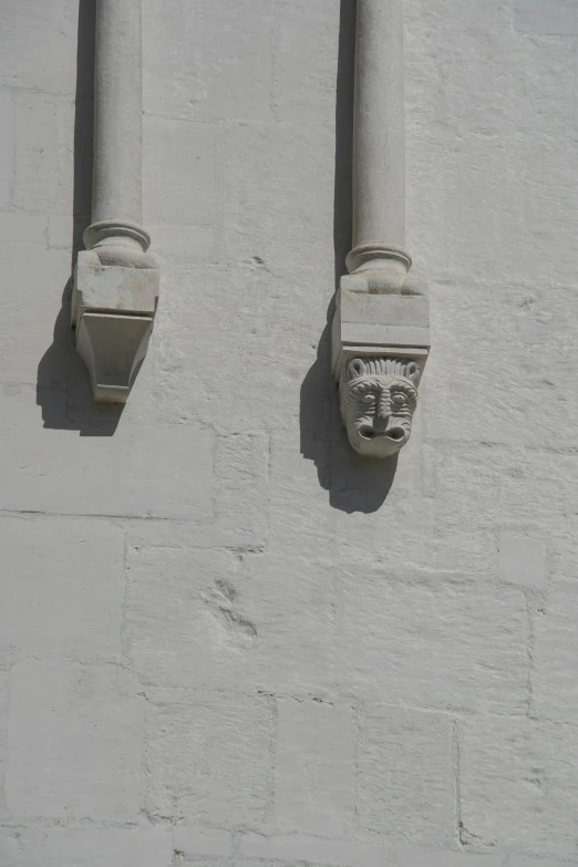 two gargoyle heads mounted to a stone wall