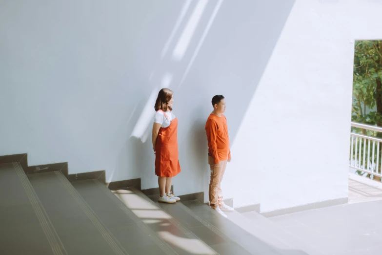 two girls stand at the top of some stairs, near a wall