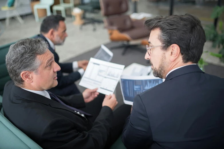 two men are discussing documents in an office setting