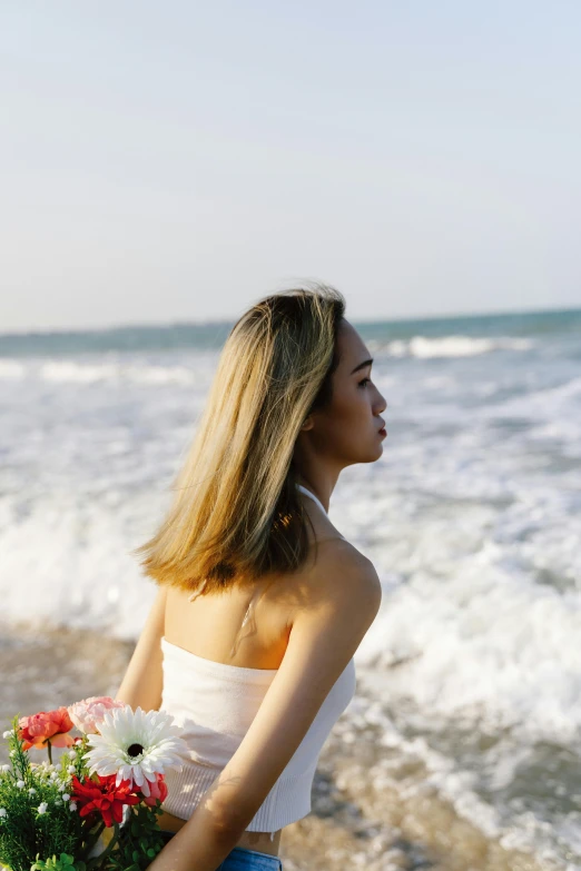 the woman is holding a bunch of flowers by the water