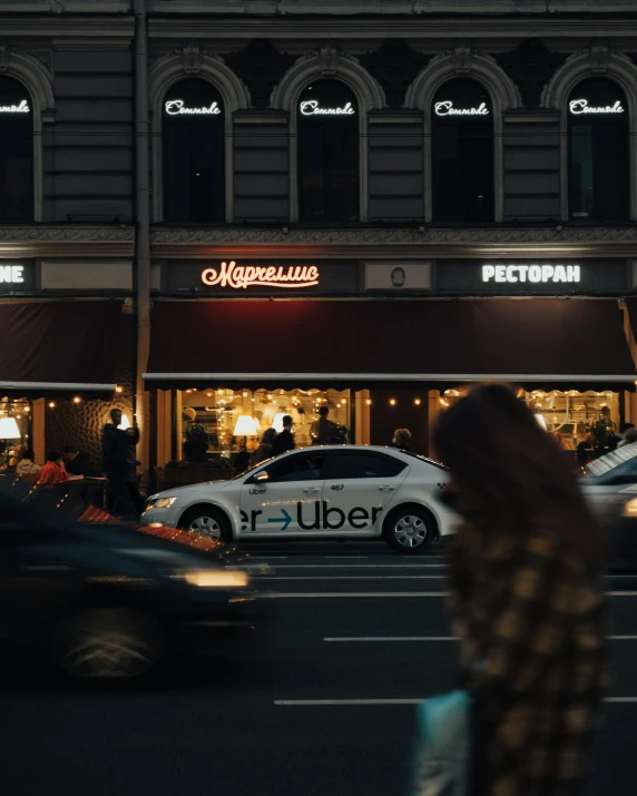 a car drives past a pub and shops at night