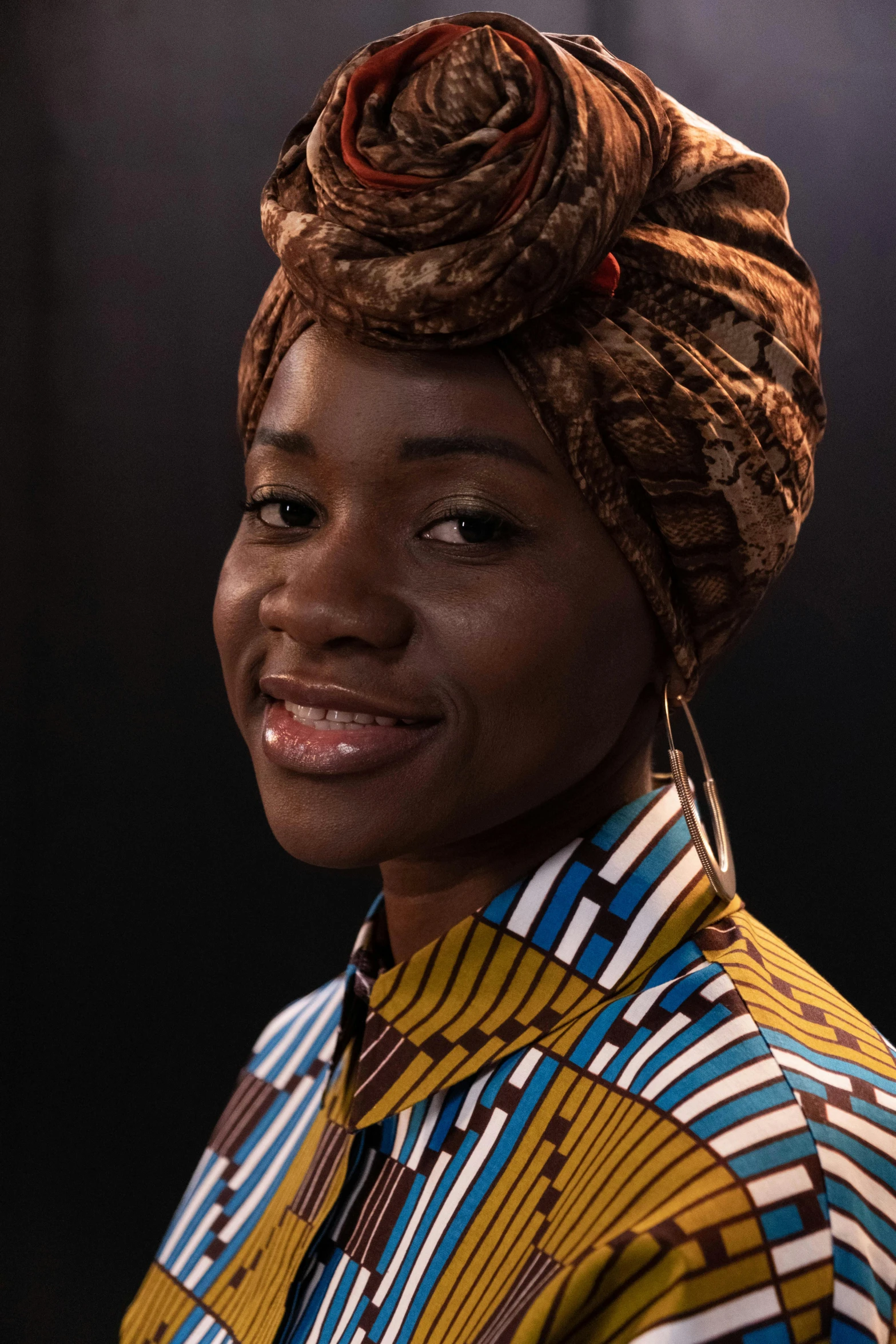 the young woman has her hair up and wearing some colorful clothing