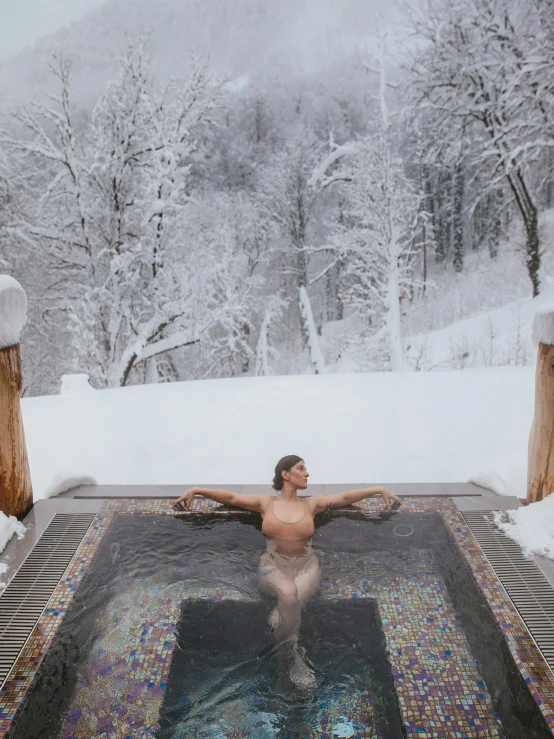 a woman standing next to a snow covered forest