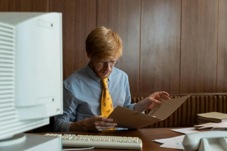 a man in suit and tie looking through work paper