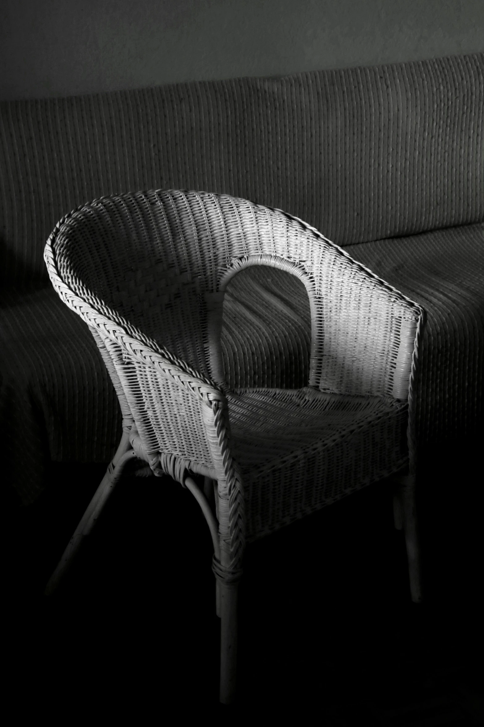 a wicker sofa and chair in a dark room