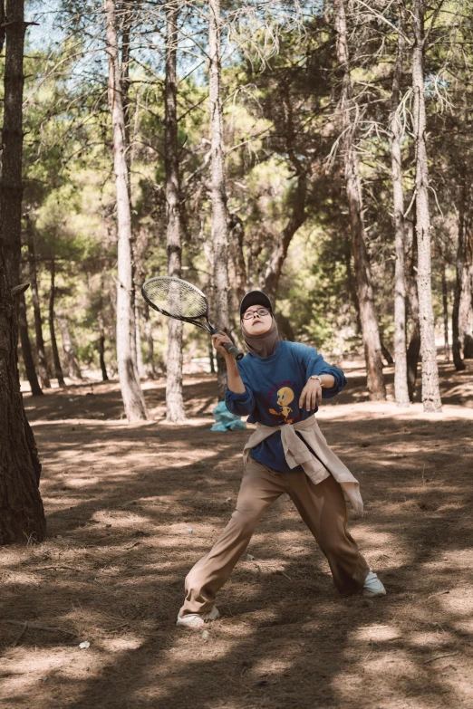 a man holding a tennis racquet near a tree