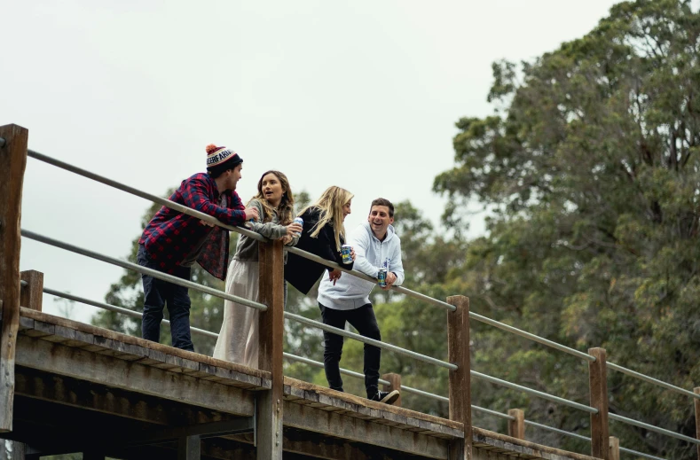 several friends on a bridge with trees in the background