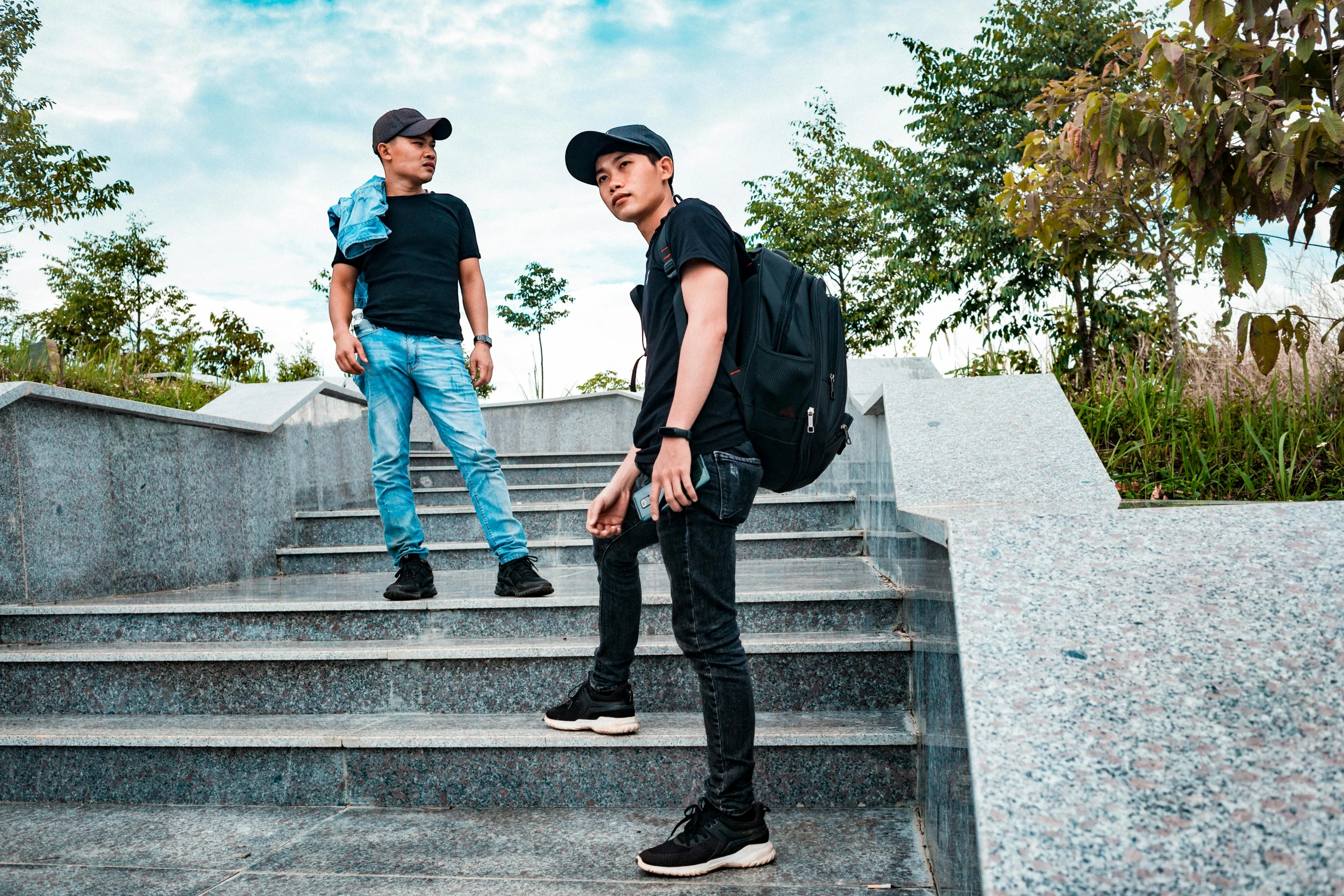 two guys are standing on the steps and one has his backpack on