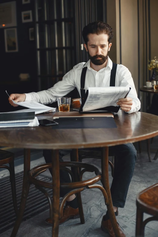 a man is sitting at a table and reading paper