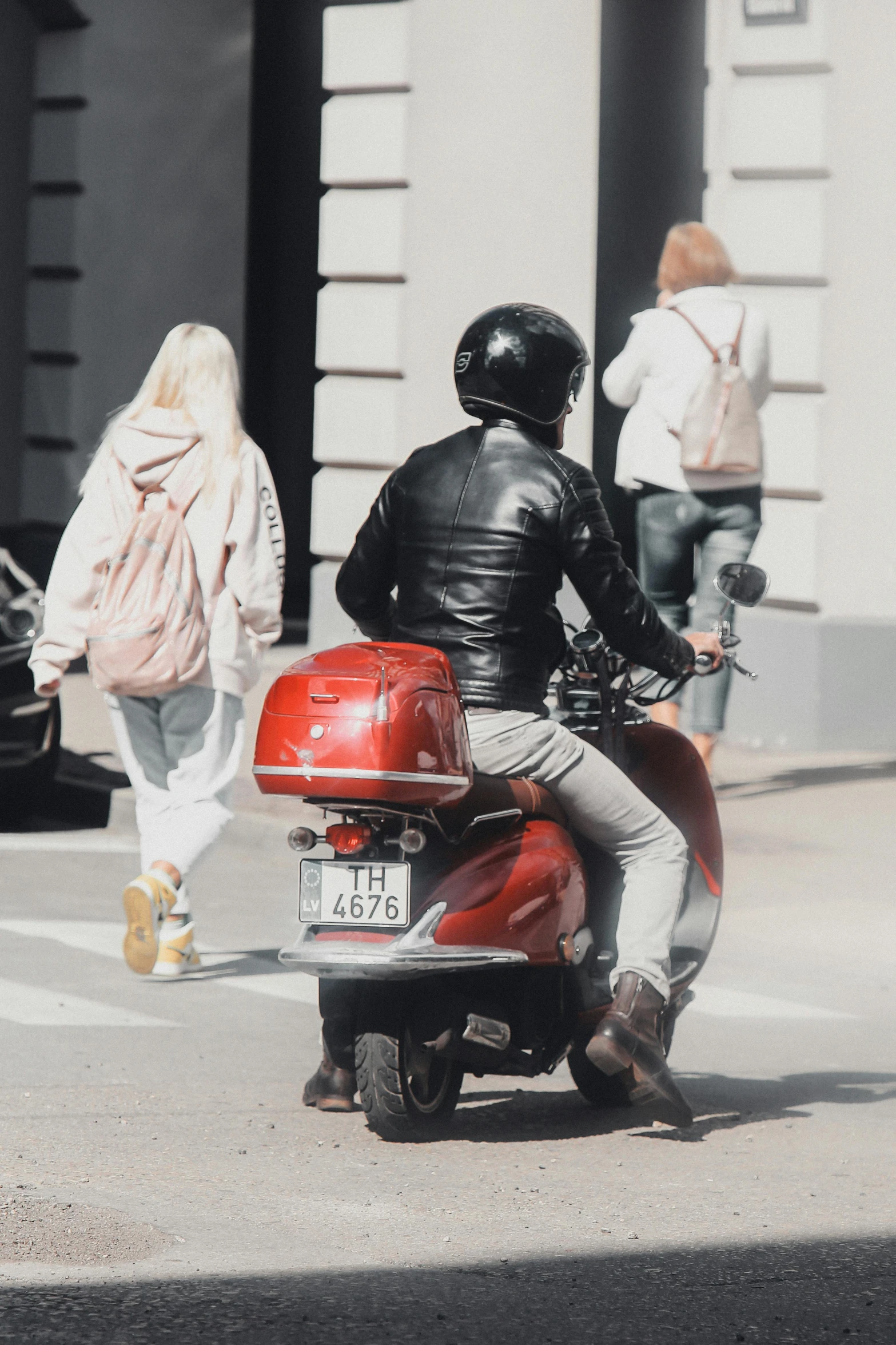 a man riding a motorcycle with a woman walking nearby