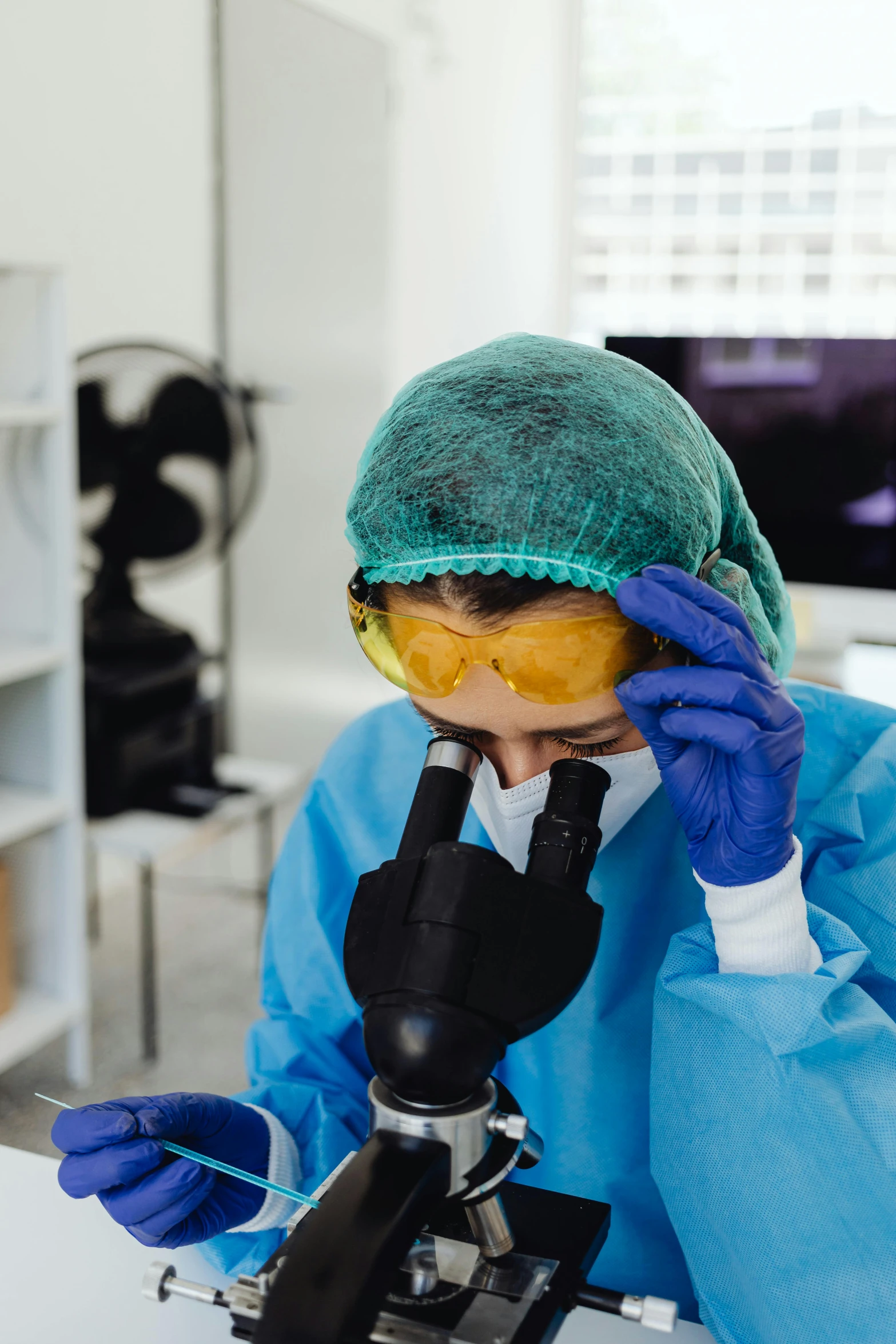 a person wearing a lab coat while looking through a microscope