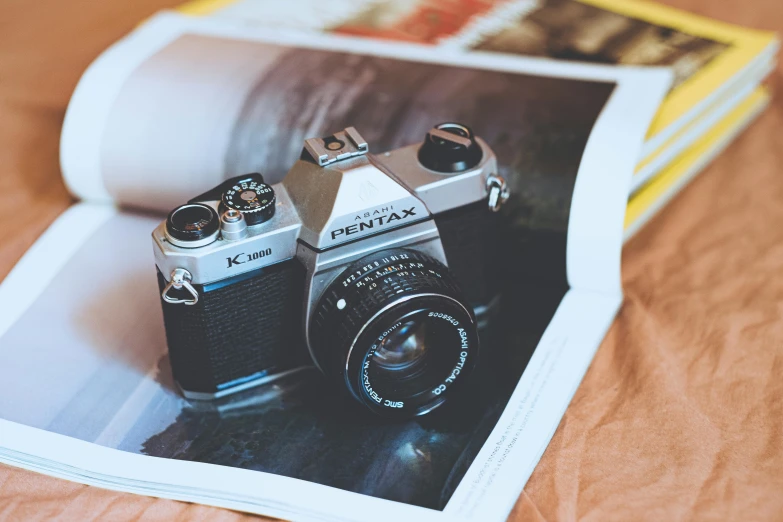 two small cameras are sitting on a magazine