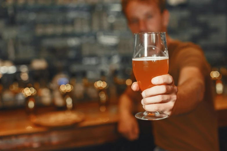 man holding up a glass of beer to the camera