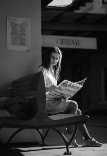a girl sitting on top of a bench reading a paper