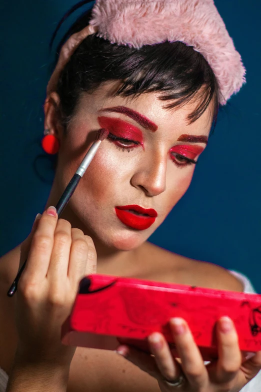 a woman holding a red device and brush her eyes