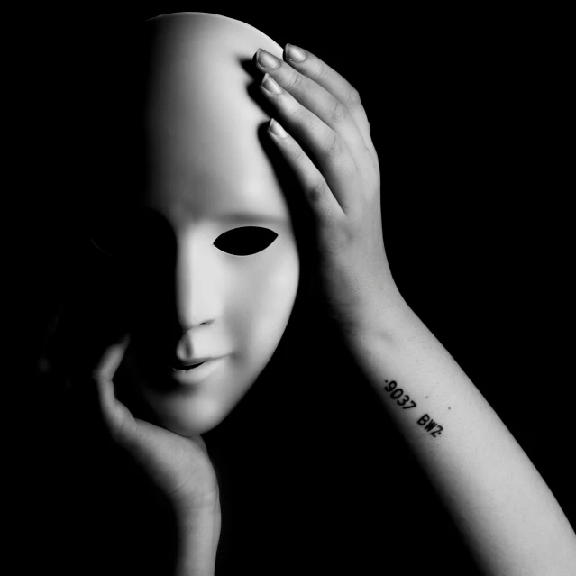 a person holding a white mask with writing on it