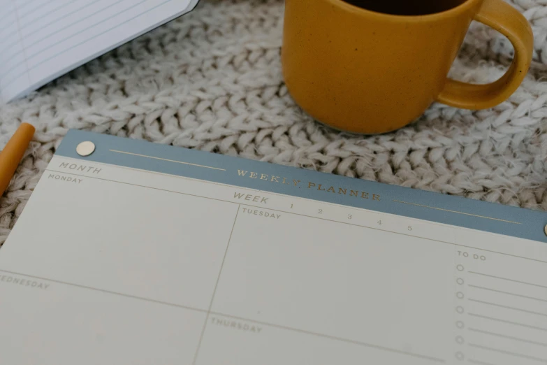 a note pad, mug and pen on a table