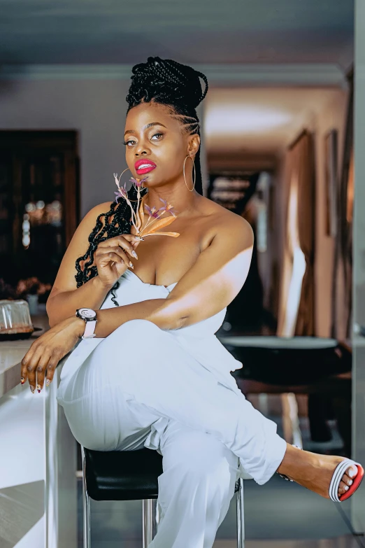 a black woman in a white outfit sitting on a bar