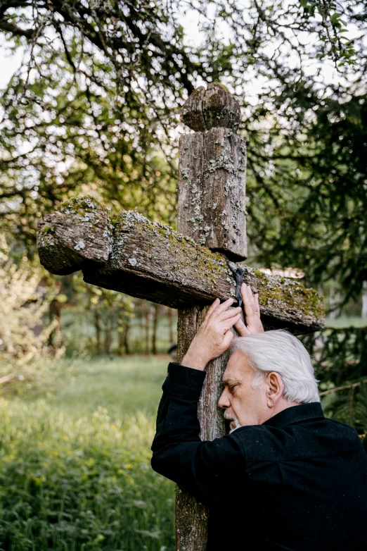 an elderly man fixing a wooden cross on a pole