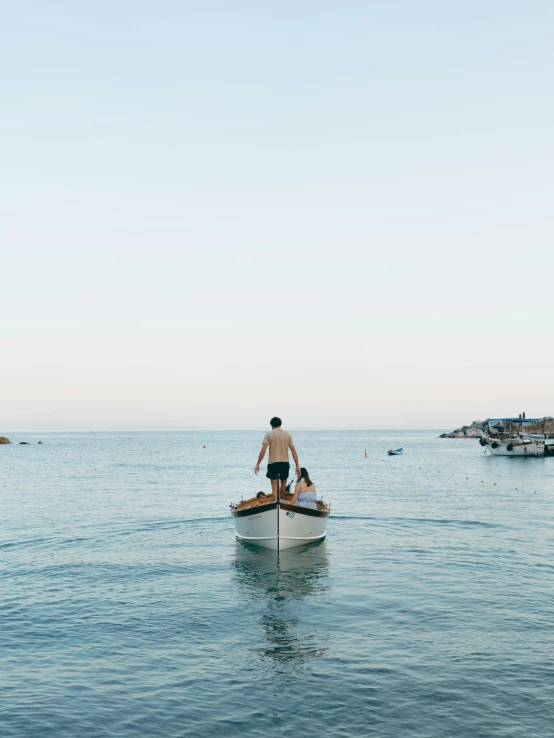 the man rows his boat towards shore as other boats are on the water