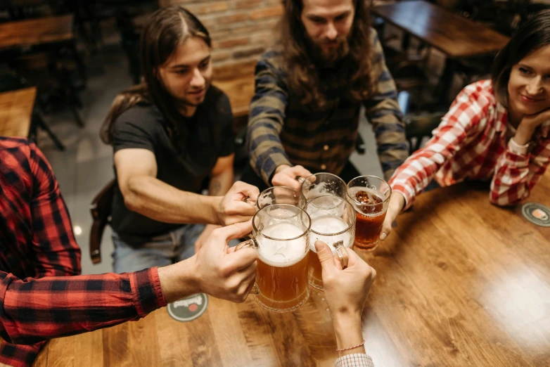 several people toasting with beers at a bar