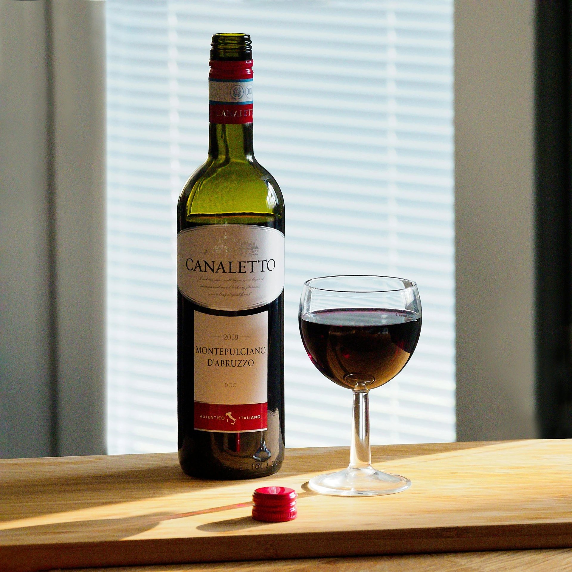 a close up of a wine glass and bottle near a window