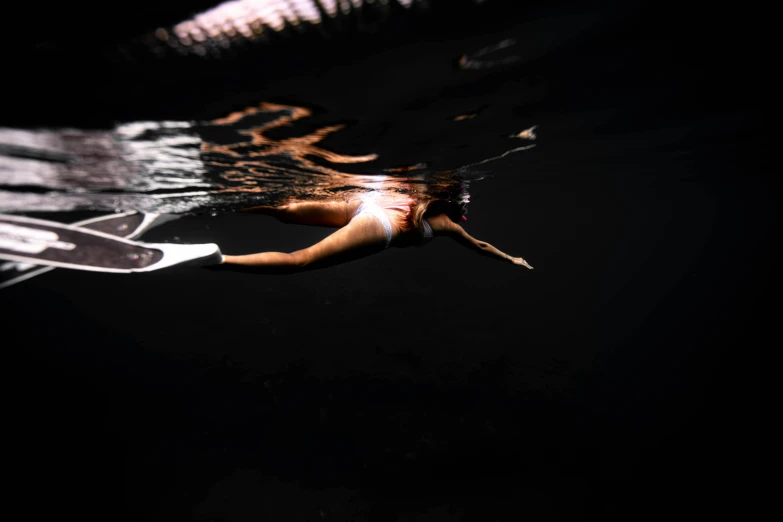 a woman is swimming underwater and holding onto a board