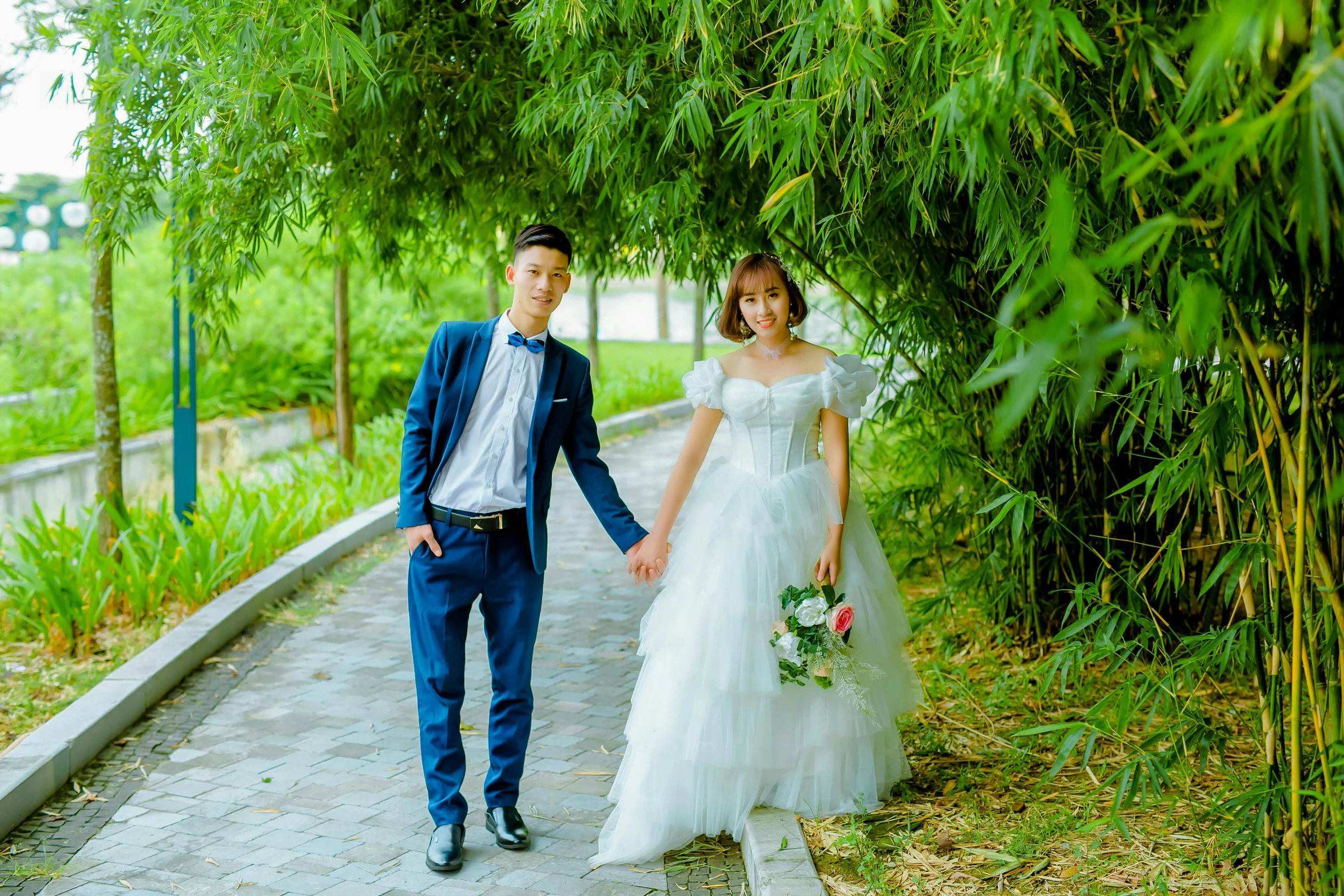 a beautiful young bride and groom walking down a path
