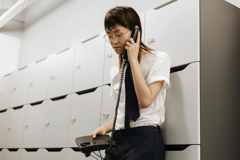 a woman is holding an old type phone and holding her cell phone to her ear