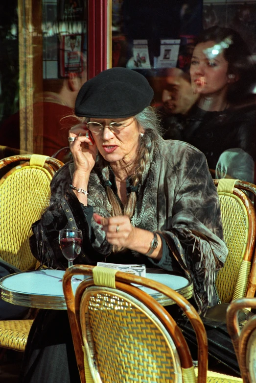 the elderly woman is sitting at an outside cafe