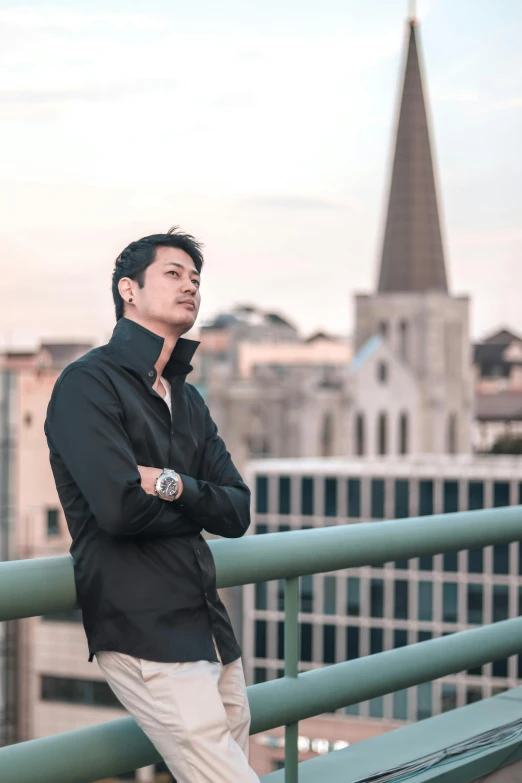 an asian man standing on a balcony overlooking a city