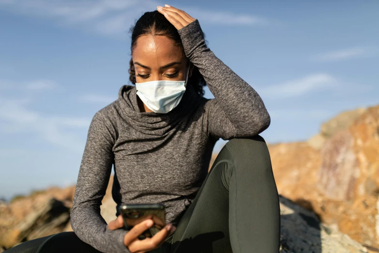 a young woman wearing a mask on her face with her cellphone