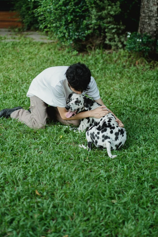 a lady is cuddling her dog on the grass