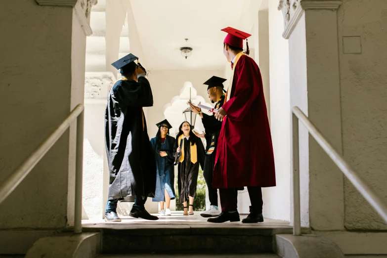 a person standing at the front of a hall with people dressed in graduation robes