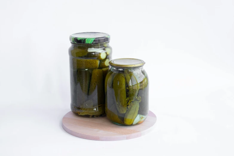 three jars full of pickles are stacked up on a stand