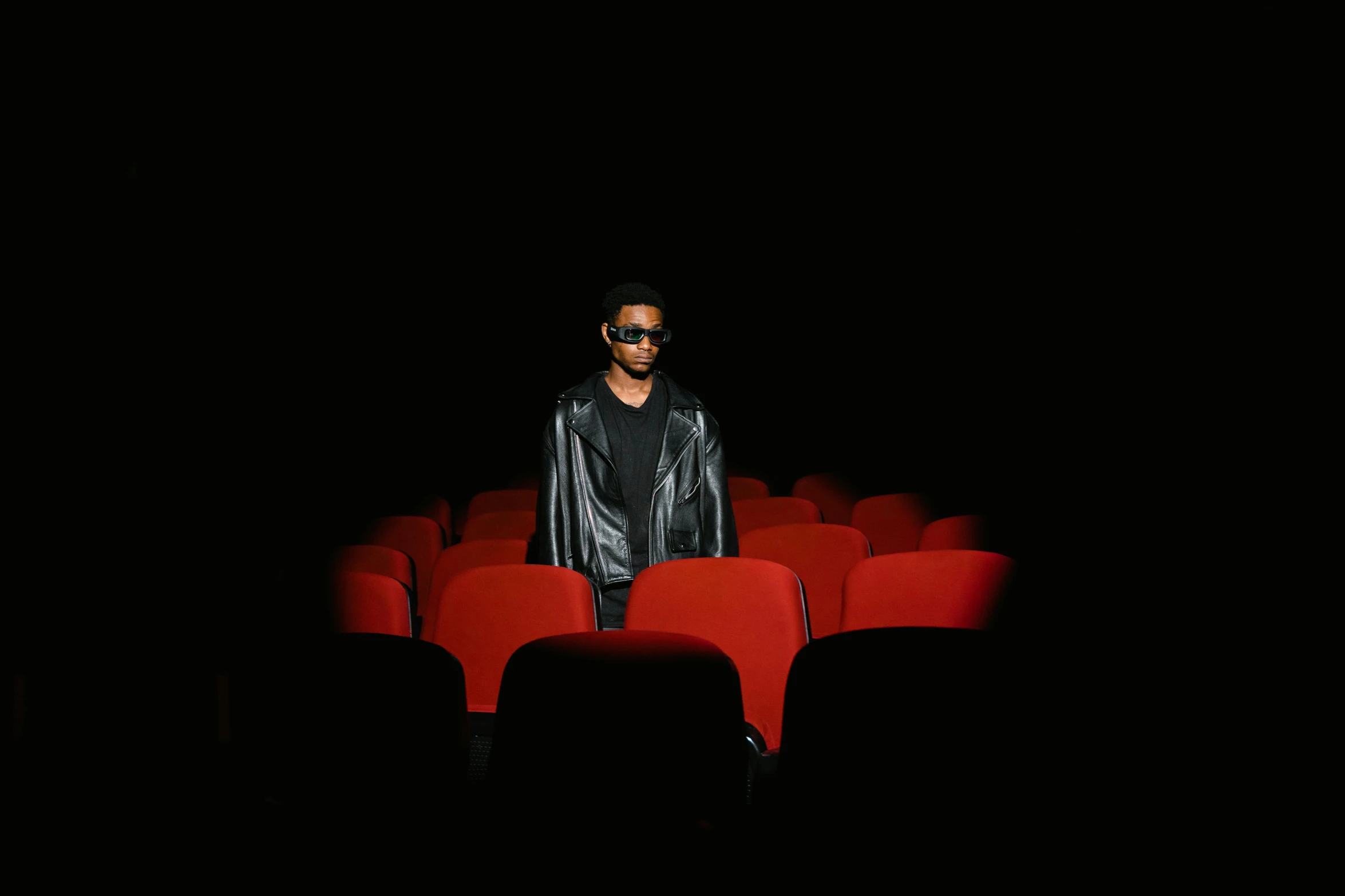 a man is standing in the middle of a red chair in the theater